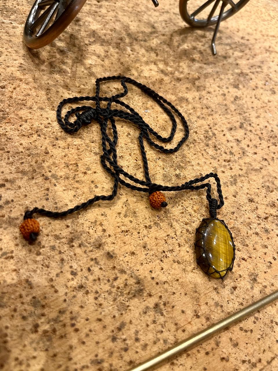 Tiger Eye pendant in macrame cord by Season Stones, showcasing a polished oval gemstone with woven cord necklace.