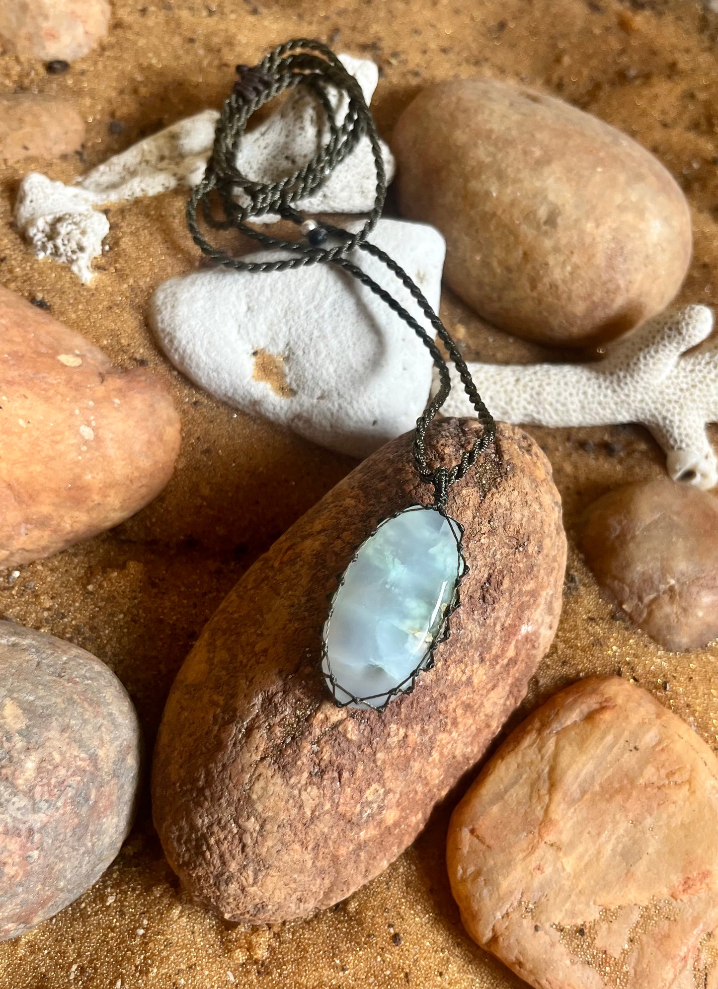 Feather agate pendant with macrame cord from Season Stones, showcasing a polished agate stone with intricate knotted cord detail.