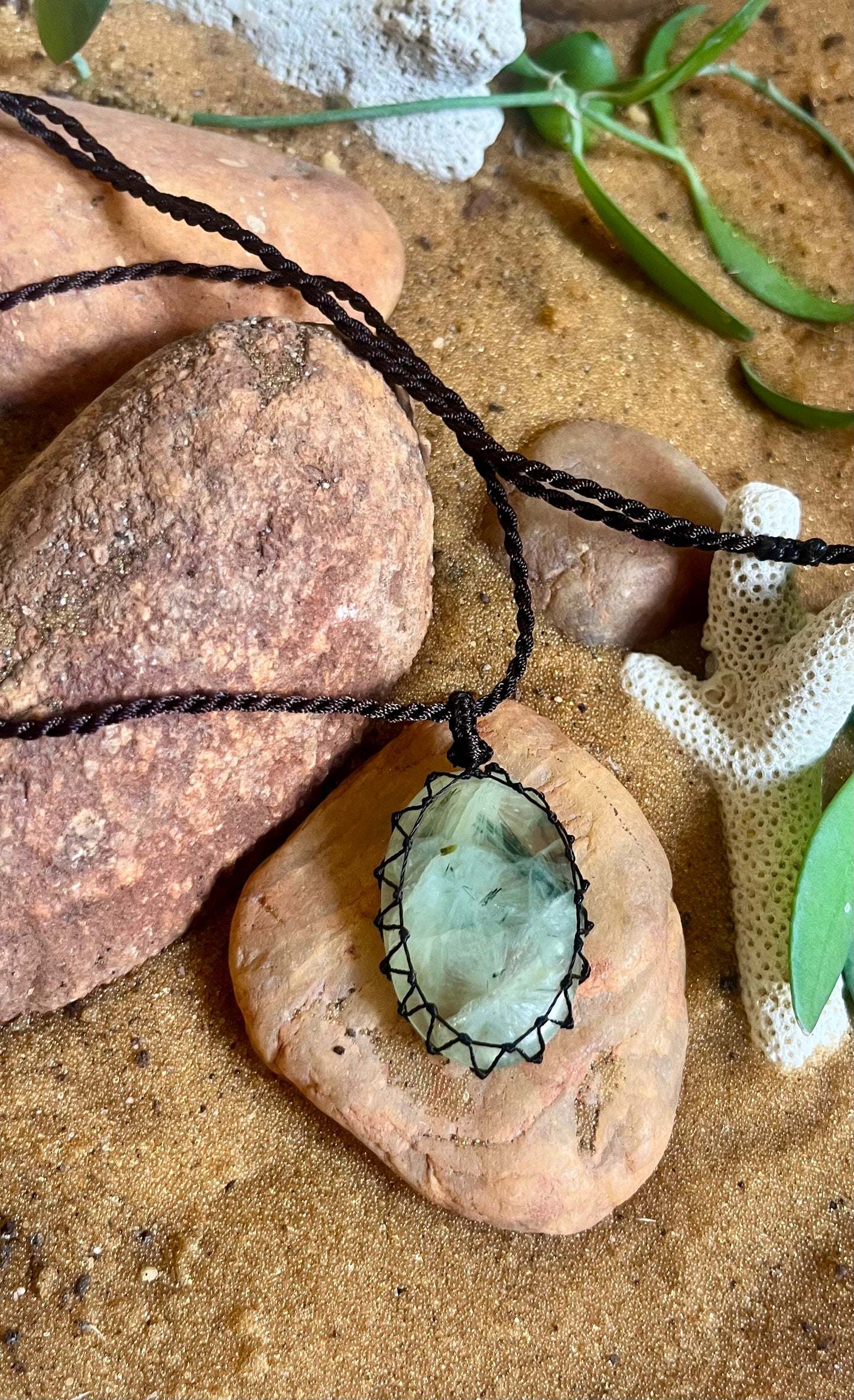 Prehnite stone pendant on a woven macrame cord with a season stones label, showcasing a polished green mineral necklace.
