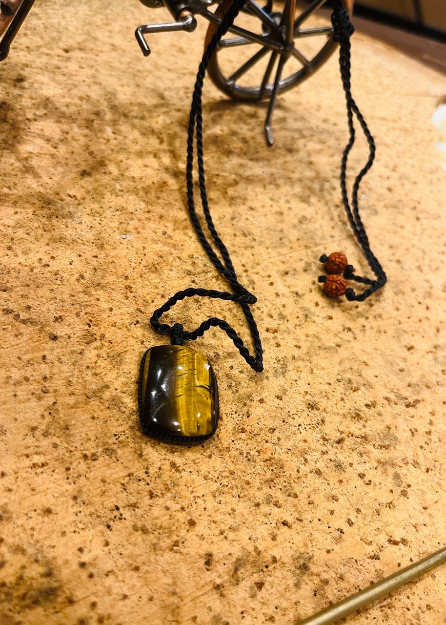 Tiger Eye pendant on macrame cord by Season Stones, showcasing a polished oval tiger eye stone with intricate knot details.