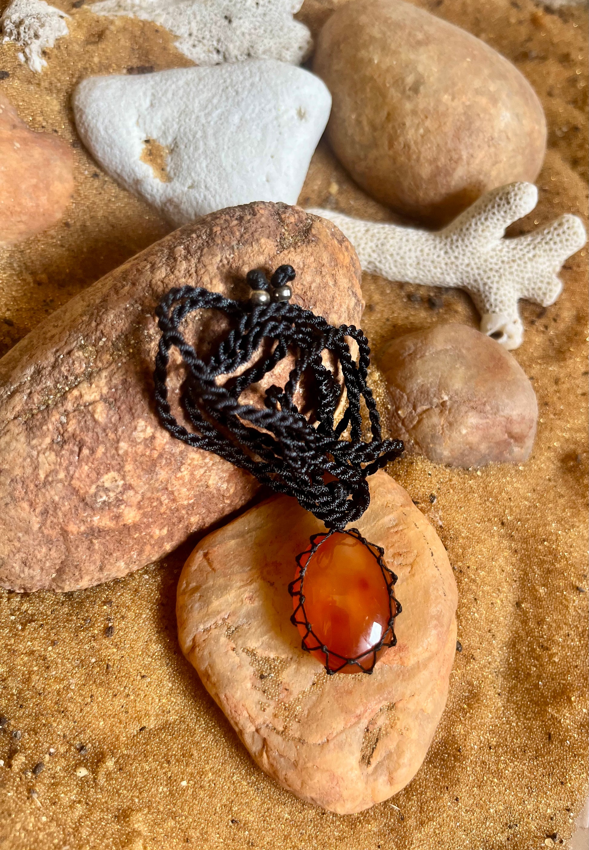 Carnelian stone in a handcrafted macrame cord necklace by Season Stones, showcasing the vibrant orange gemstone and intricate knotting.